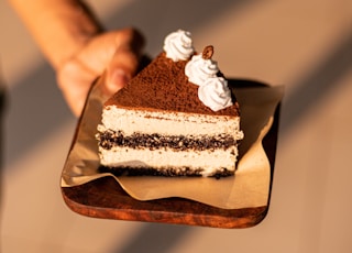 a person holding a piece of cake on a plate