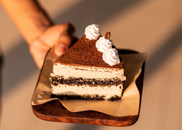 a person holding a piece of cake on a plate