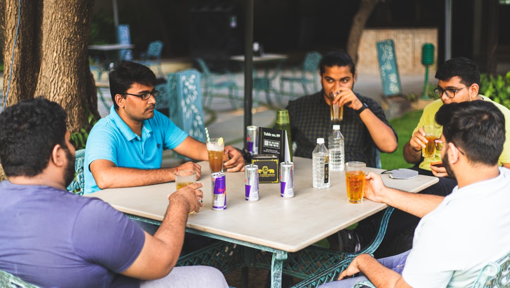 a group of men sitting around a table with drinks