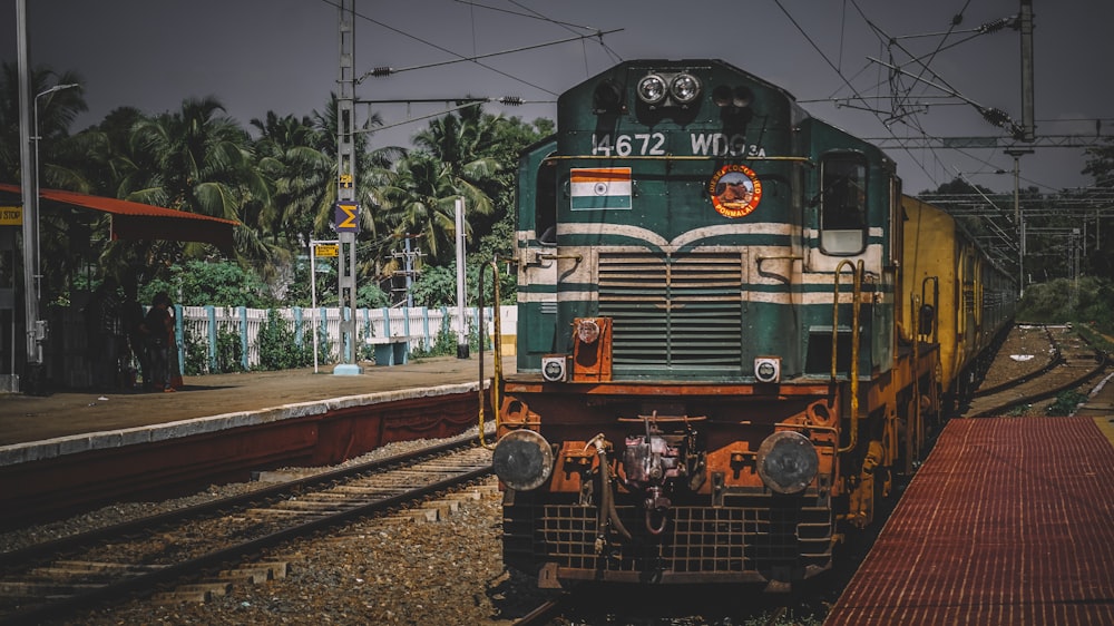 a green and yellow train traveling down train tracks