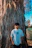 a young man standing in front of a palm tree