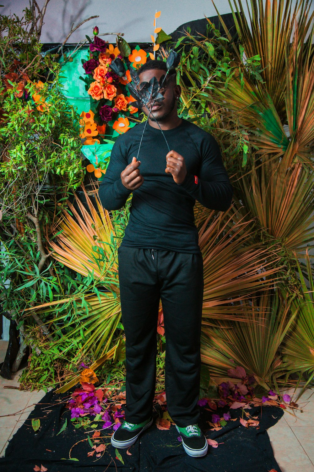 a man wearing a mask standing in front of plants