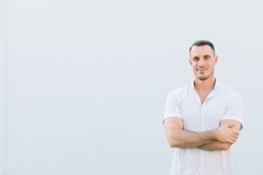 a man standing with his arms crossed in front of a white wall
