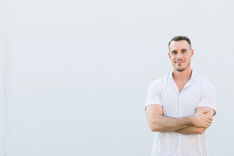 a man standing with his arms crossed in front of a white wall