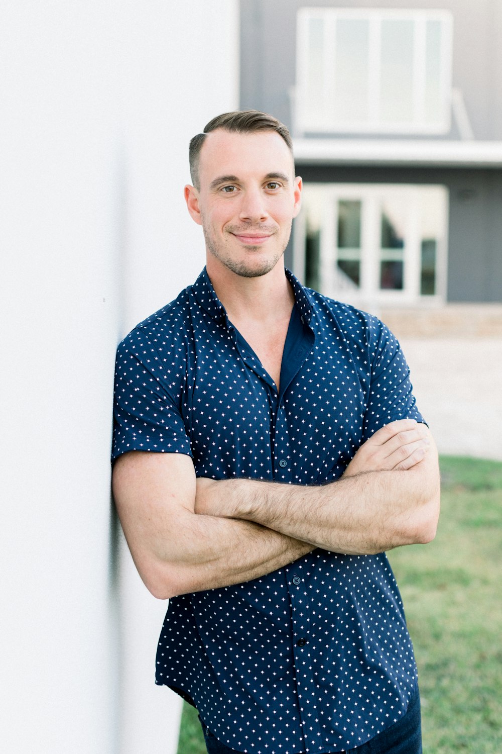 a man with his arms crossed leaning against a wall