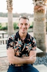 a man sitting on a bench in front of palm trees