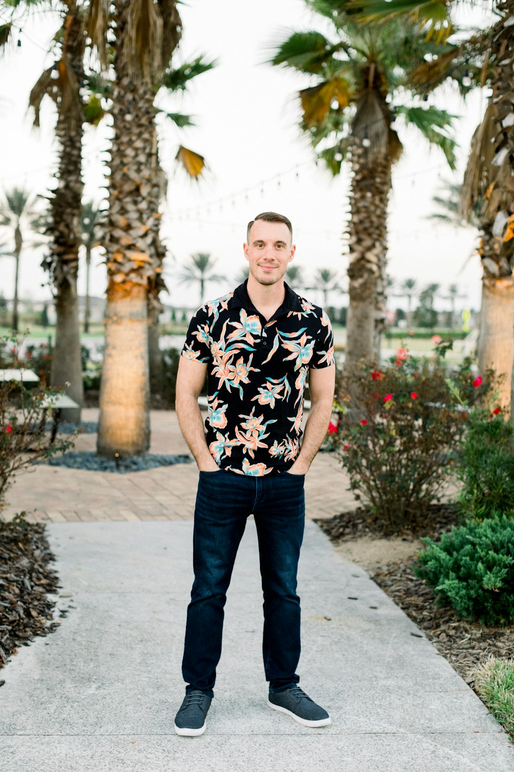 a man standing on a sidewalk in front of palm trees