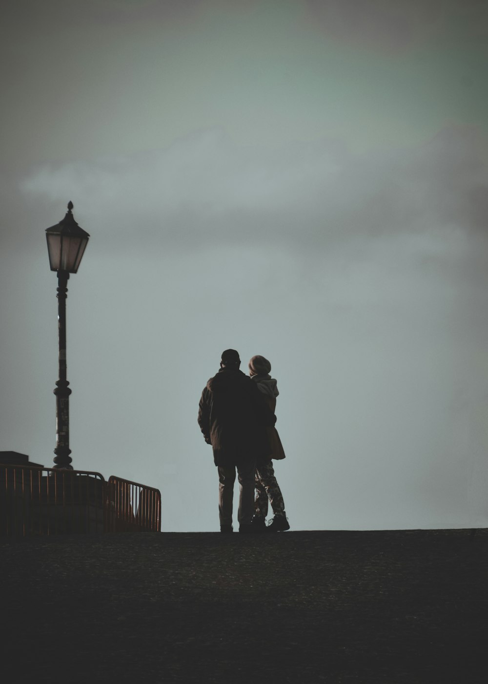 two people standing next to each other near a street light