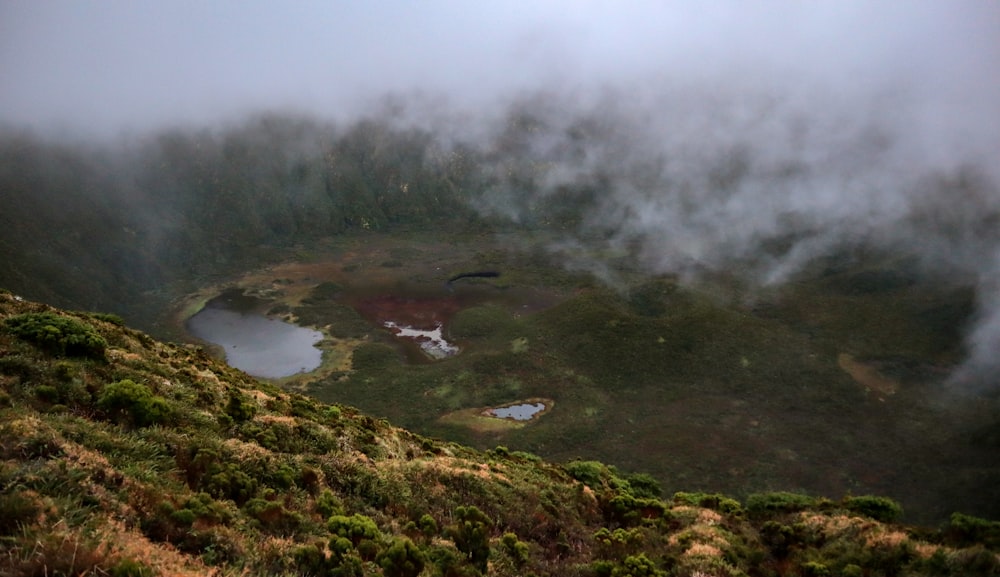 a foggy mountain with a small lake in the middle