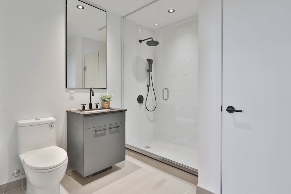 a bathroom with a toilet, sink, shower and mirror