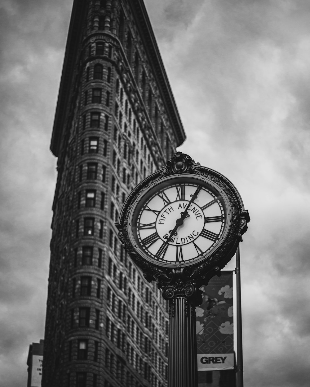 a clock on a pole in front of a tall building