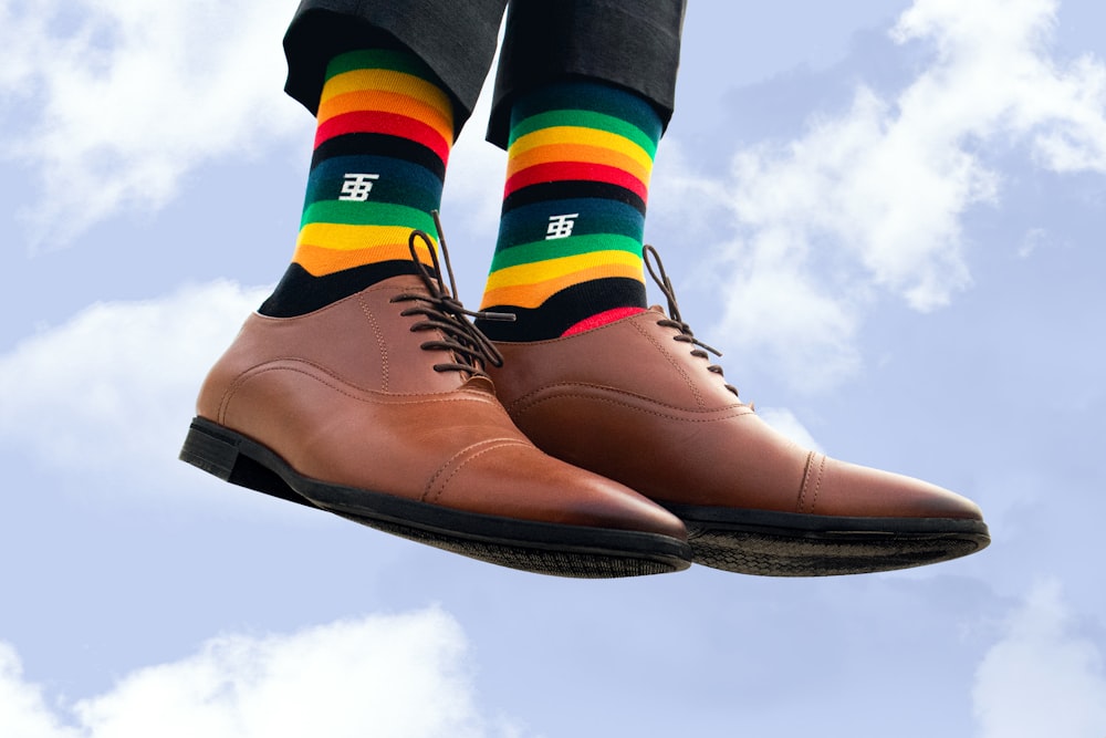 a person wearing a pair of striped socks and brown shoes