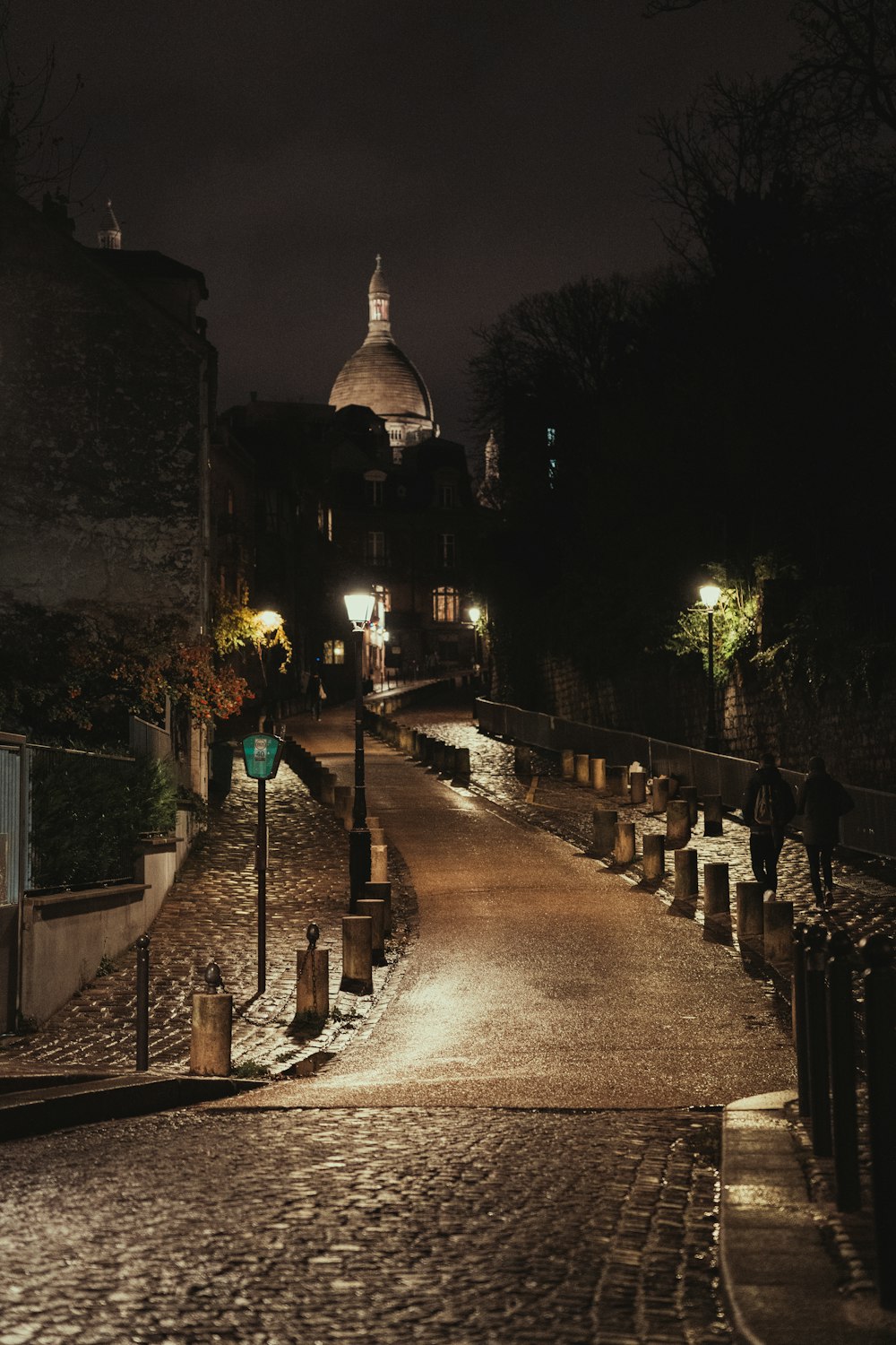 a cobblestone street at night with a church in the background
