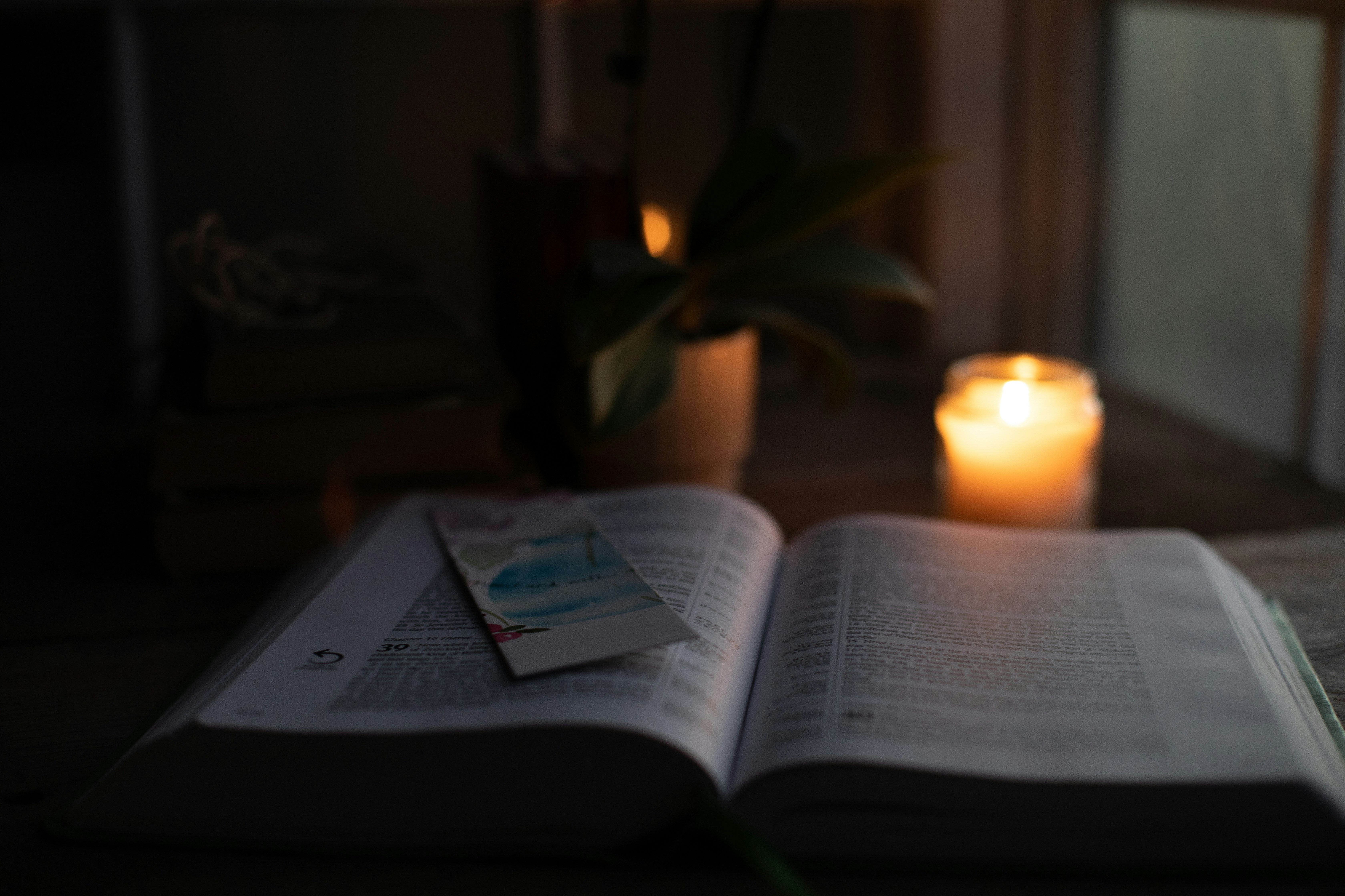 an open book sitting on top of a table next to a candle