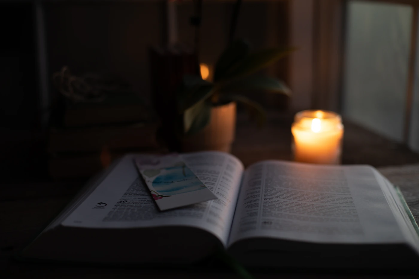 An open book beside a lit candle, set for quiet prayer and reading