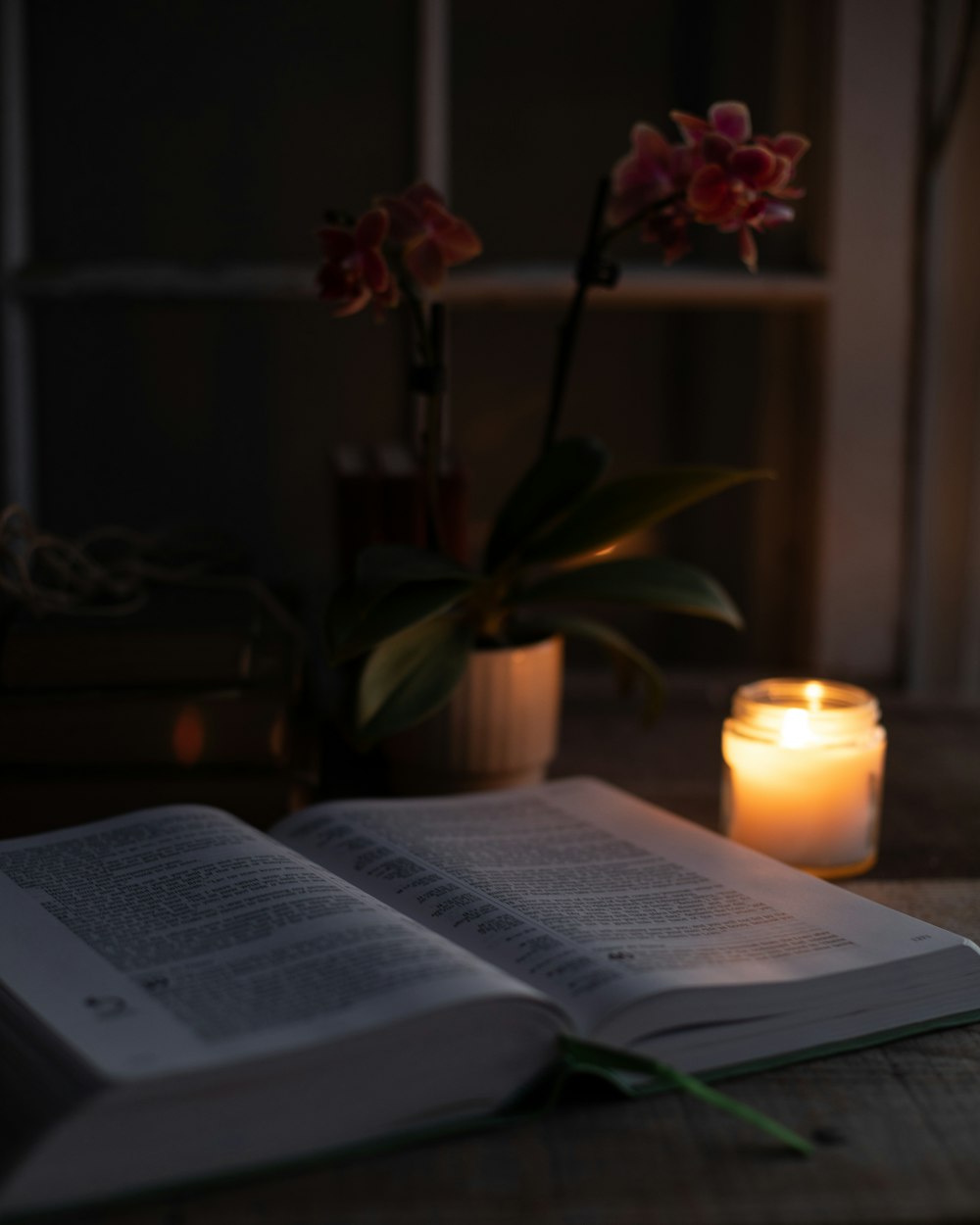 an open book sitting on top of a table next to a candle
