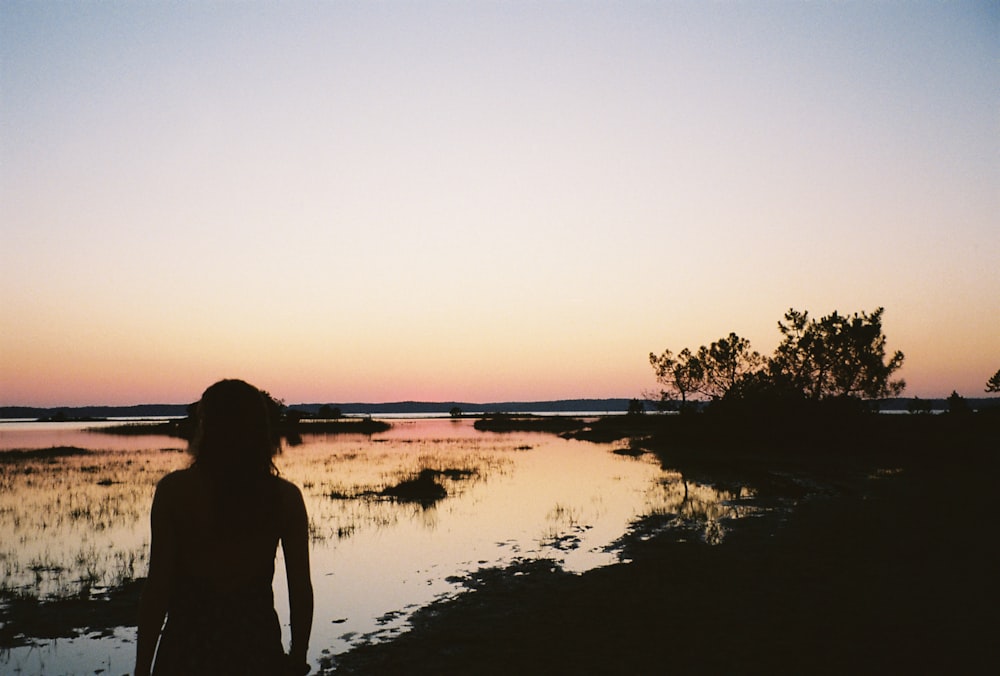 a woman standing in front of a body of water