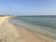 A peaceful beach scene in Hua Hin with colorful umbrellas and gentle waves lapping the sand.