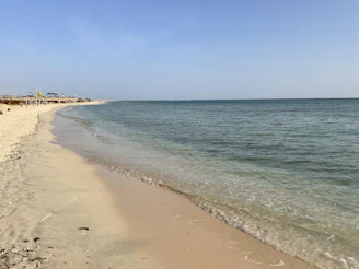 A peaceful beach scene in Hua Hin with colorful umbrellas and gentle waves lapping the sand.