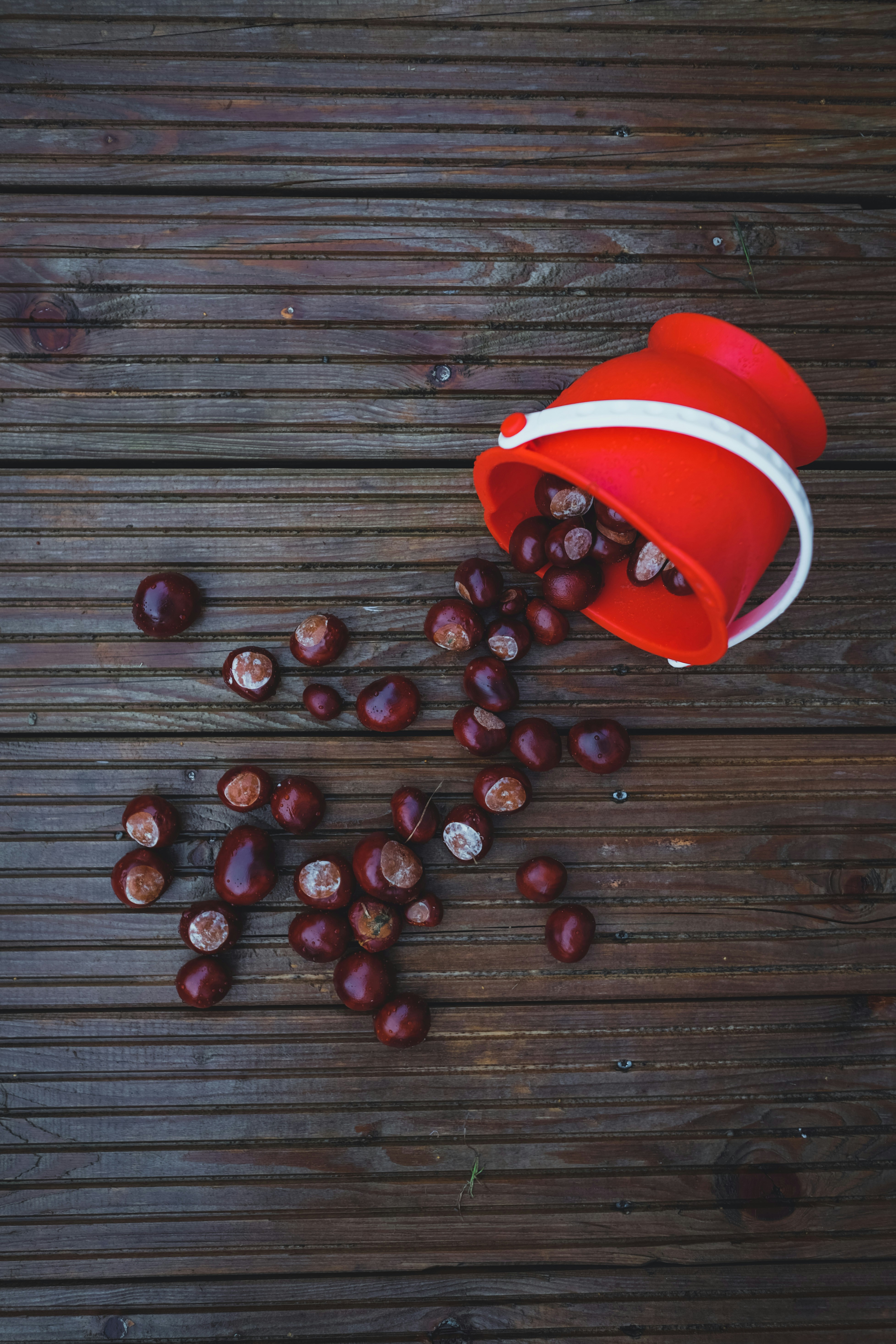 una taza roja llena de cerezas encima de una mesa de madera