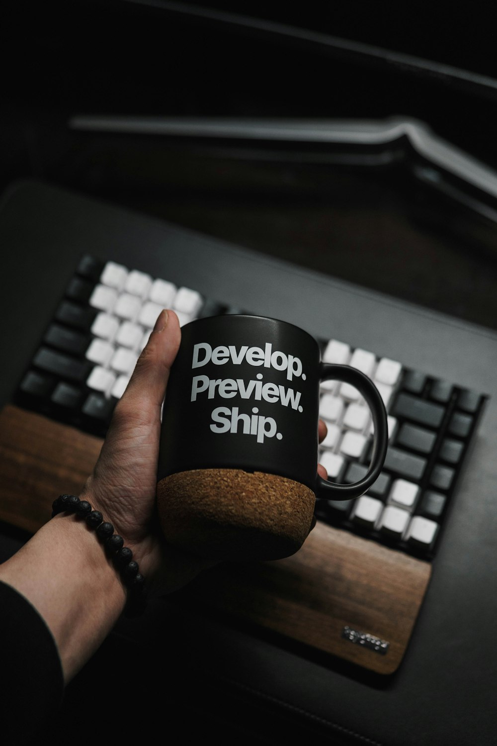 a person holding a coffee mug in front of a keyboard