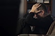 a man sitting on a couch holding his head in his hands