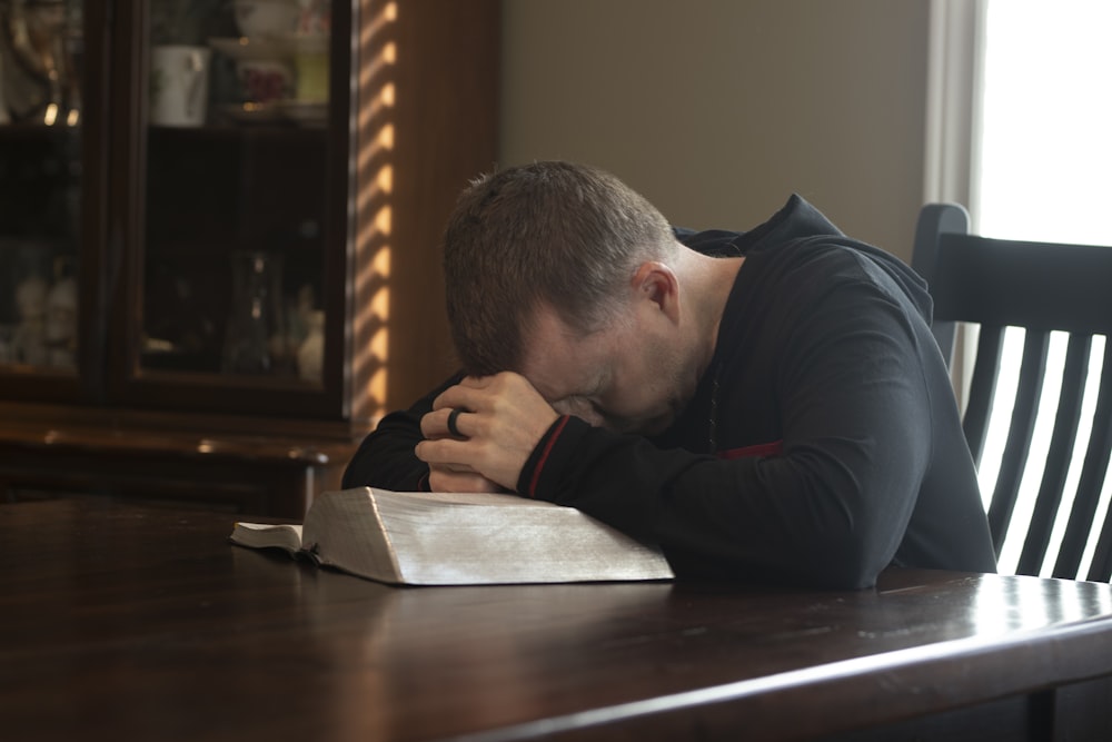 a man sitting at a table with his head in his hands