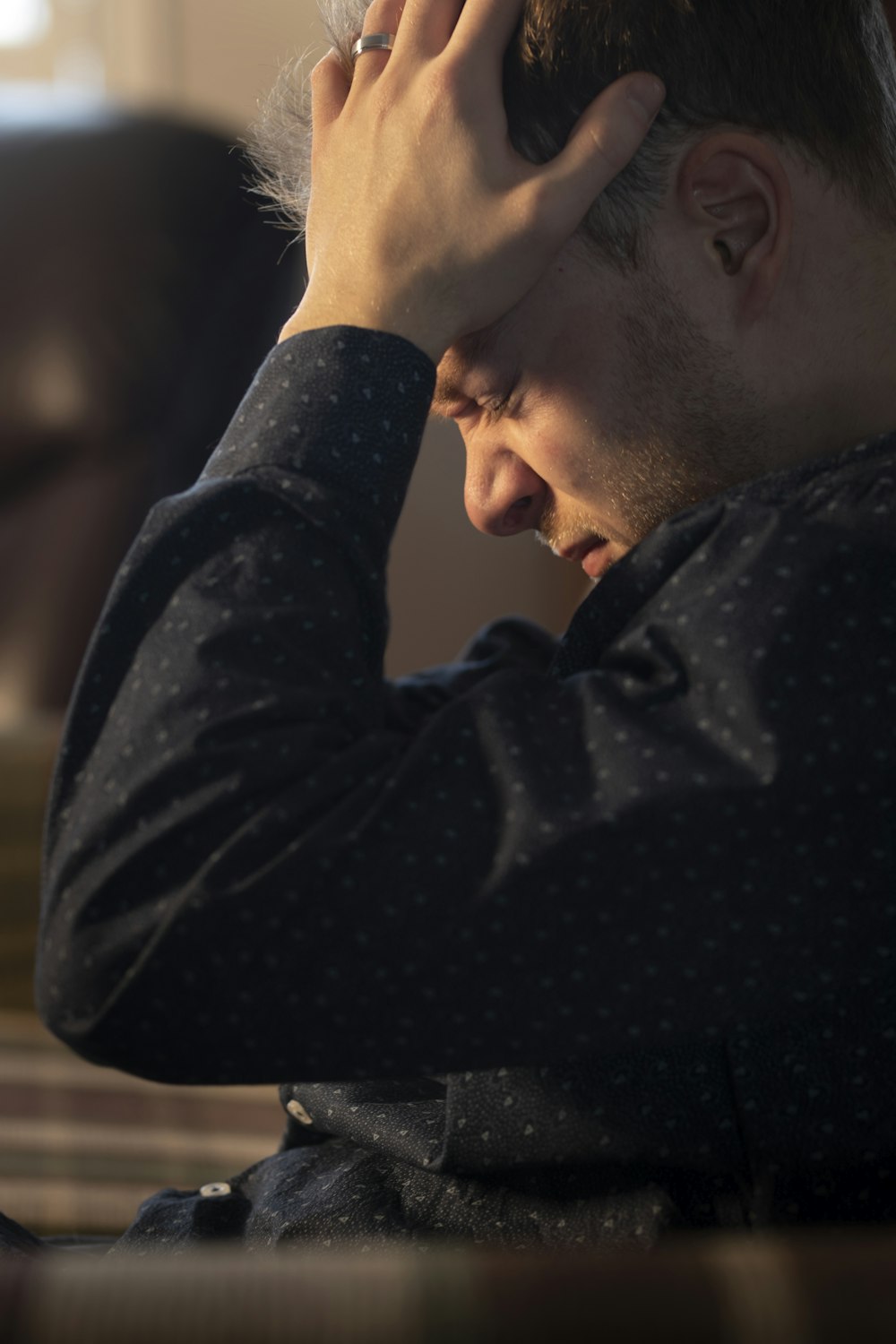 a man sitting at a table with his hand on his head