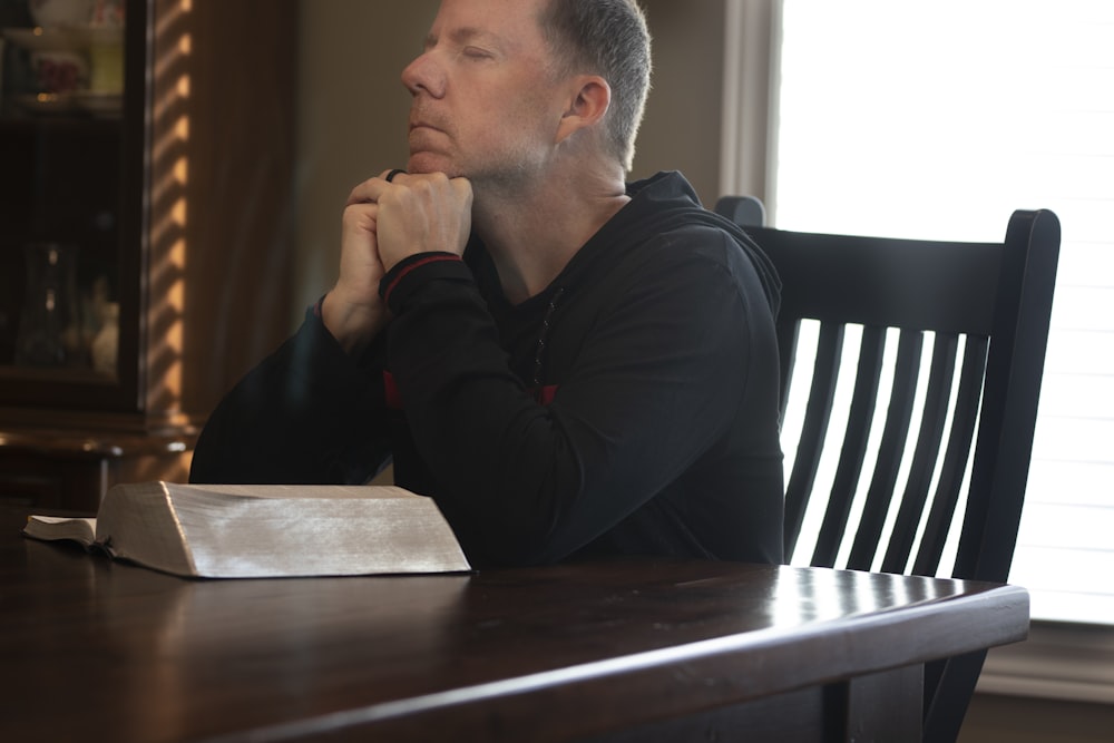 a man sitting at a table with his hands folded