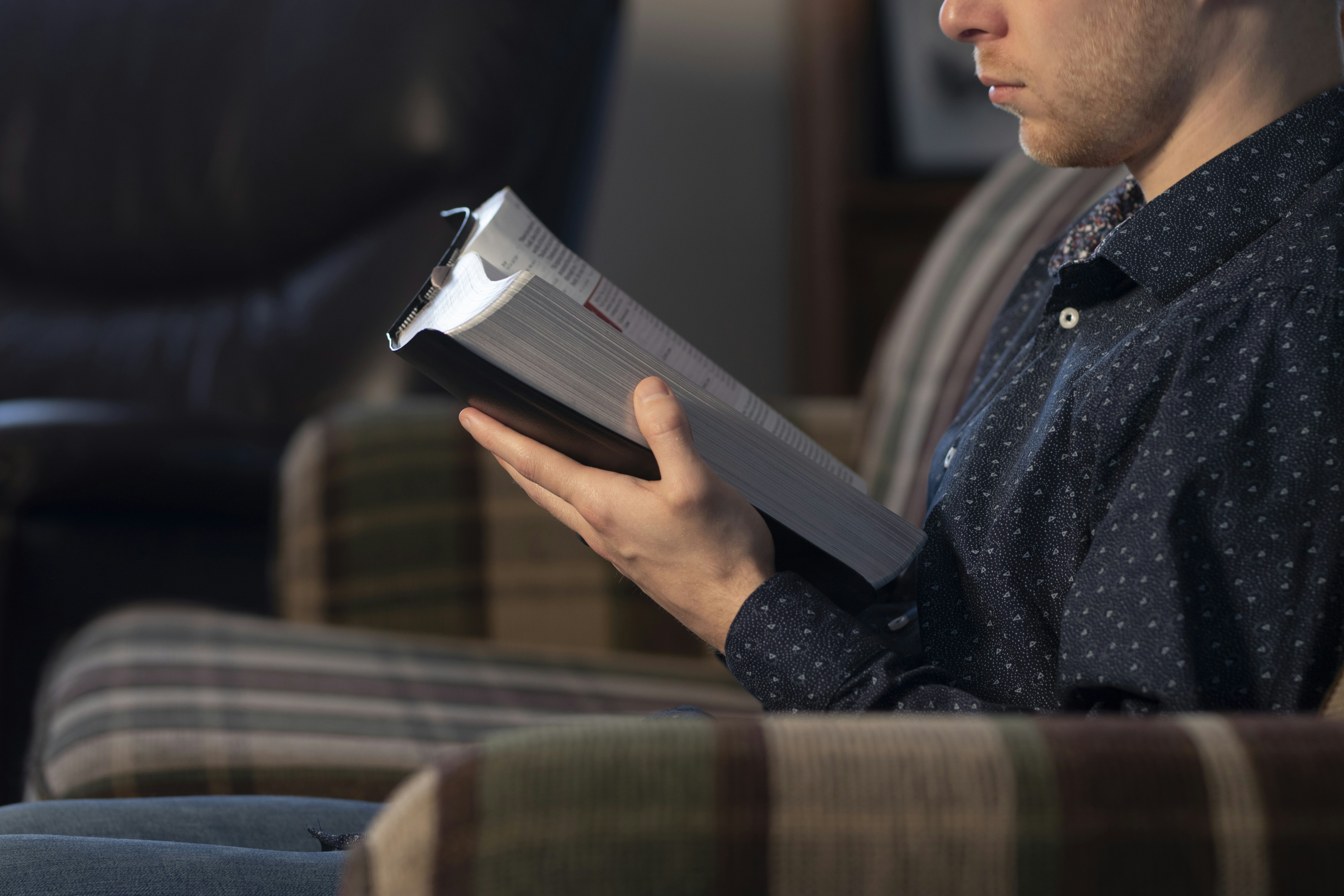 Young man reading bible on couch