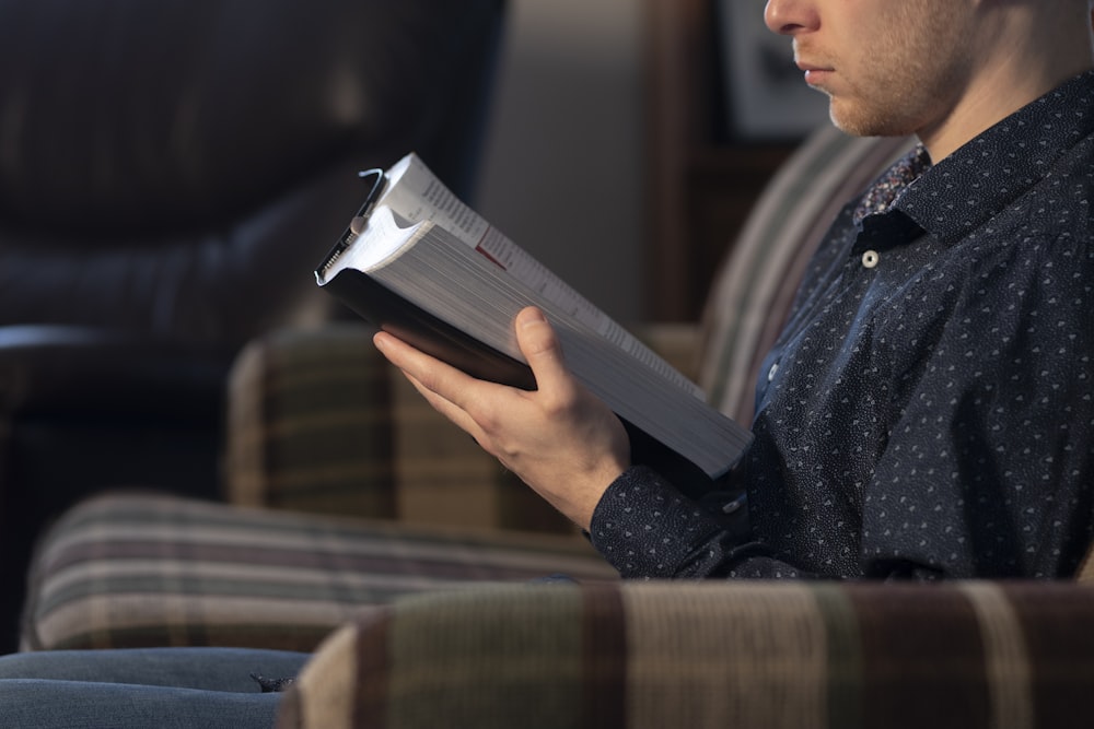 a man sitting on a couch reading a book