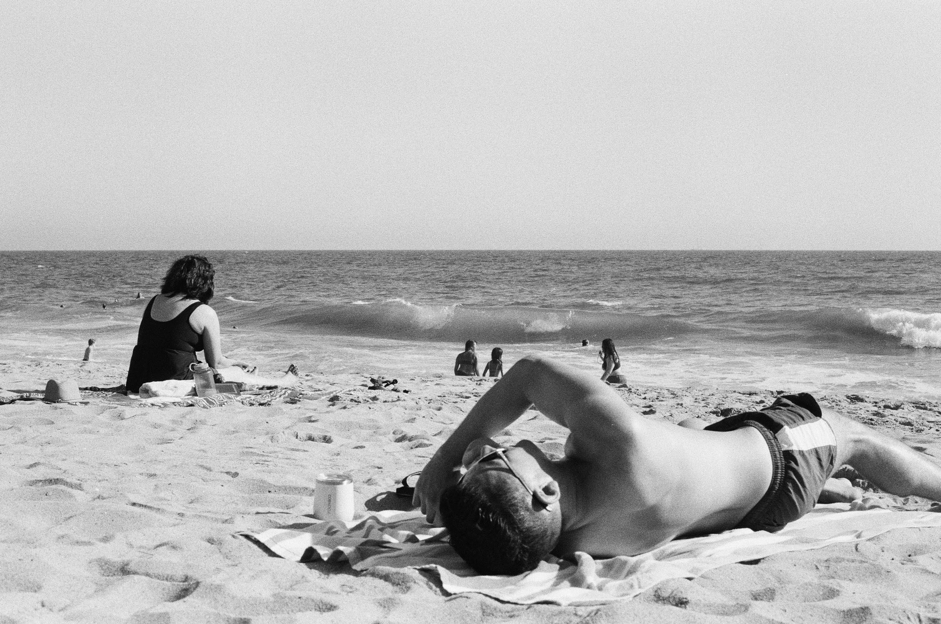 a man laying on top of a beach next to the ocean