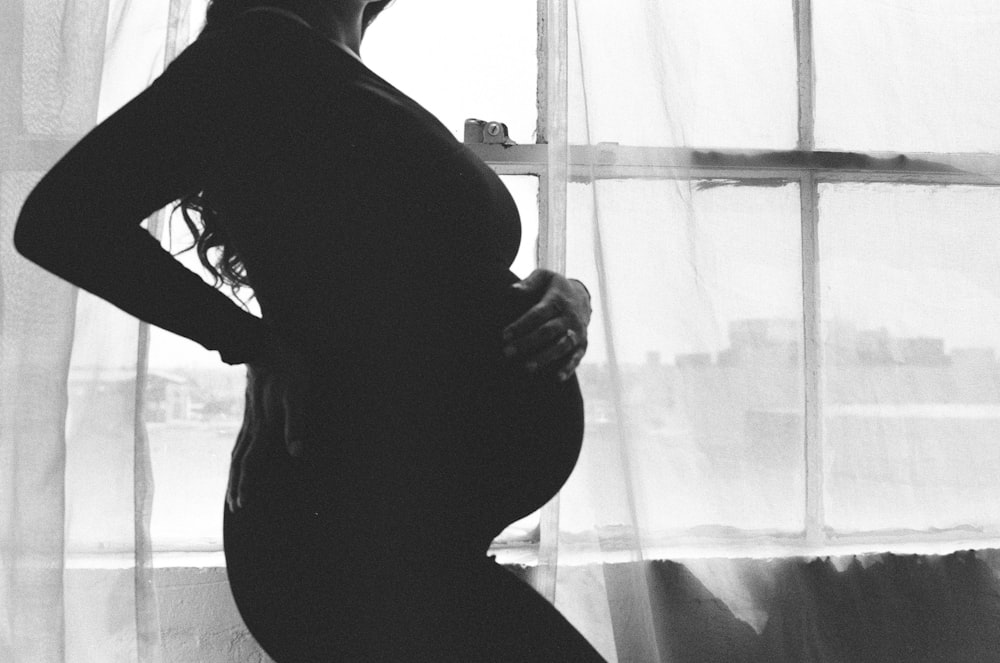 a pregnant woman standing in front of a window