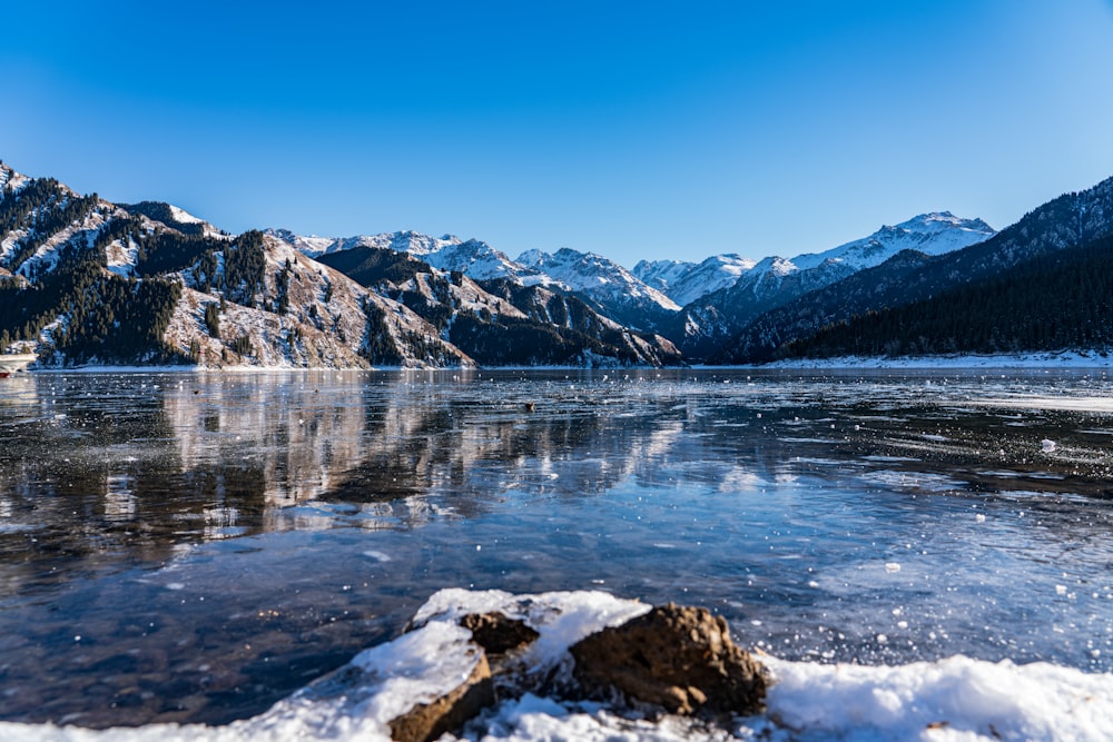 Ein zugefrorener See umgeben von Bergen und Schnee