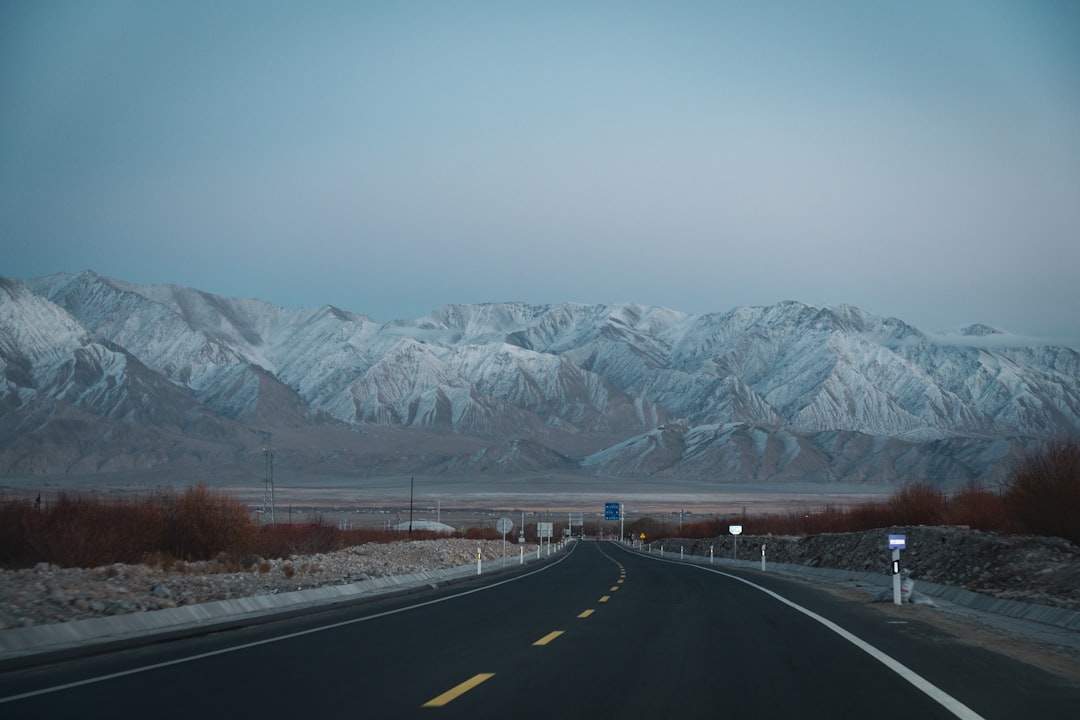 a road with a mountain range in the background, 新疆喀什地区塔什库尔干县境内的雪山