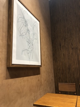 A detailed botanical illustration print framed on a wooden wall.