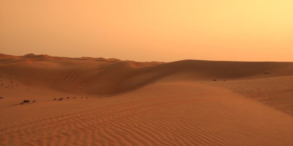 the sun is setting over the sand dunes