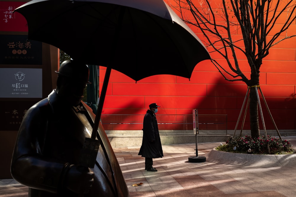 a statue of a man holding an umbrella in front of a building