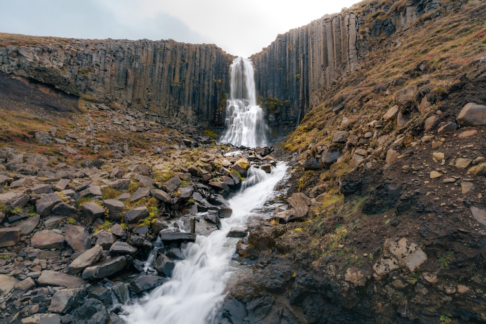 a large waterfall is coming out of a rocky cliff