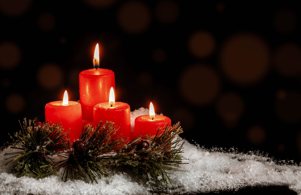 Un gruppo di candele rosse sedute in cima a un mucchio di neve