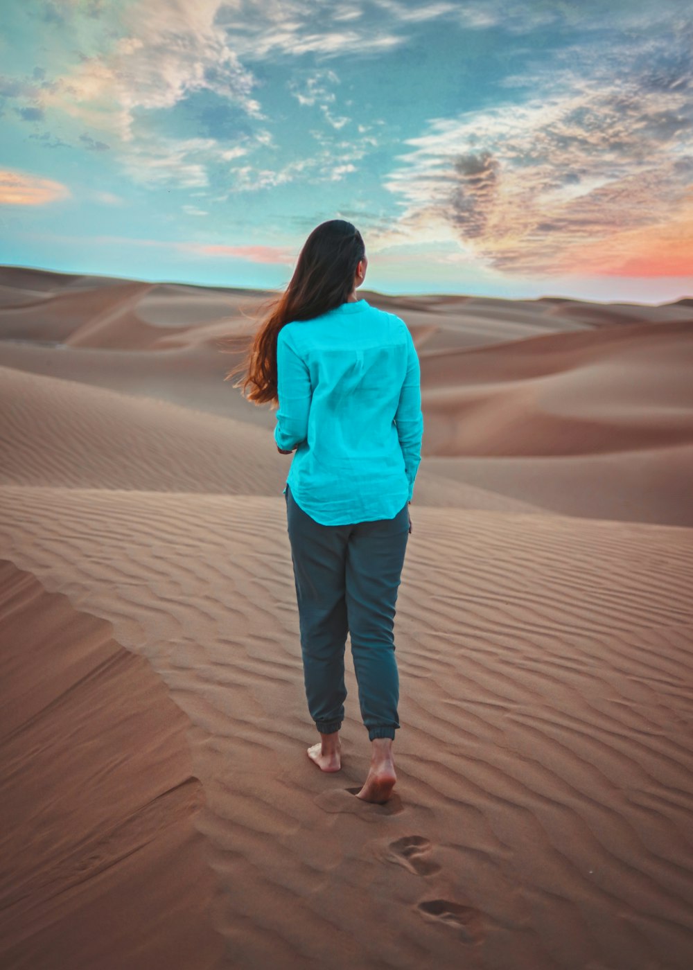 a woman standing in the middle of a desert