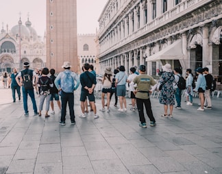 a group of people standing on a street next to a tall building