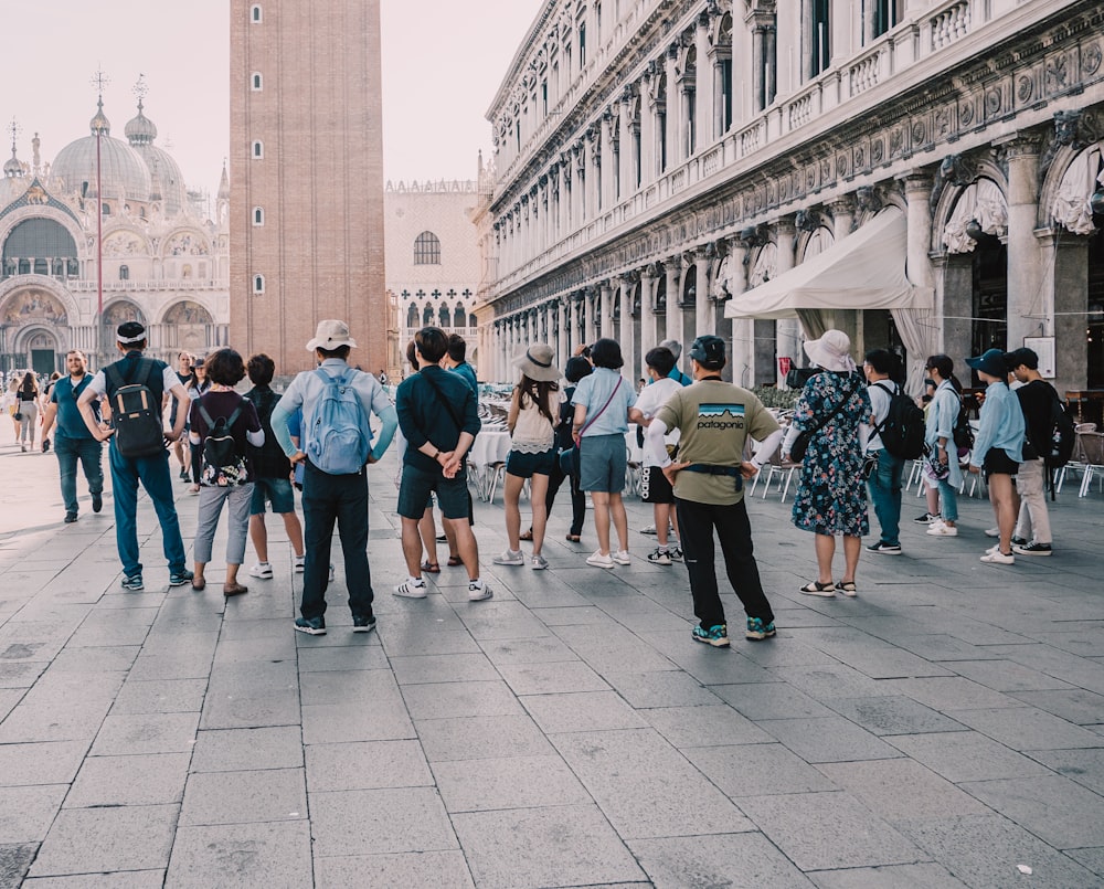 a group of people standing on a street next to a tall building