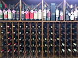 Close-up of a rustic wooden wine rack filled with various Greek wine bottles at Ampelos.