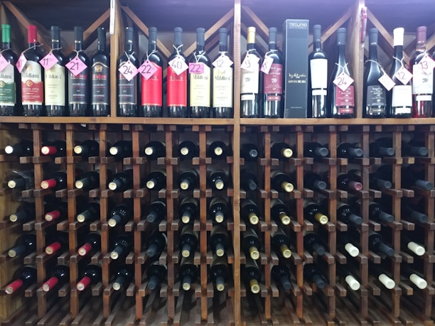A rustic wooden wine rack filled with various bottles of red, white, and rosé wines in a cozy cellar.