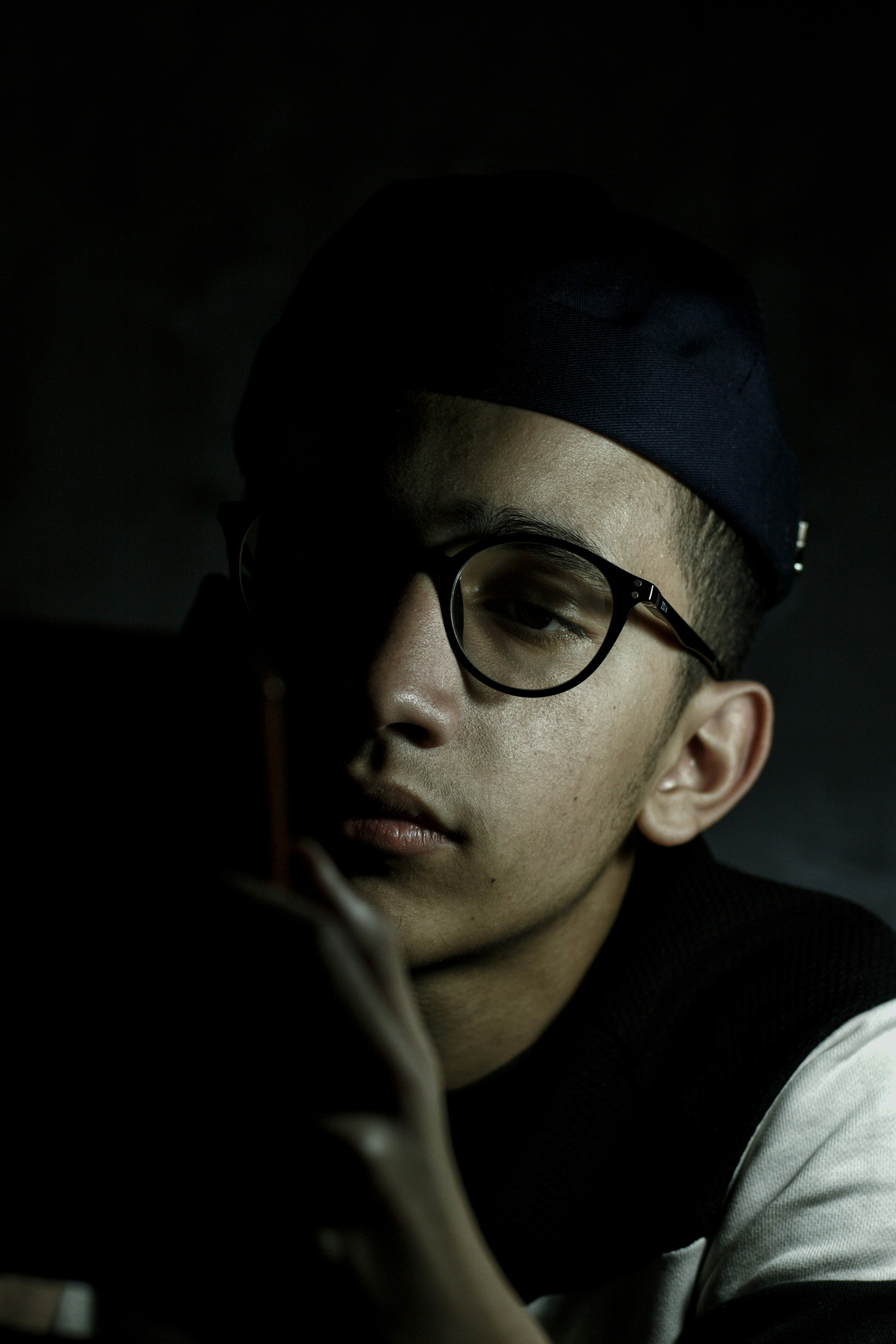 a man wearing glasses and a cap is looking at a cell phone