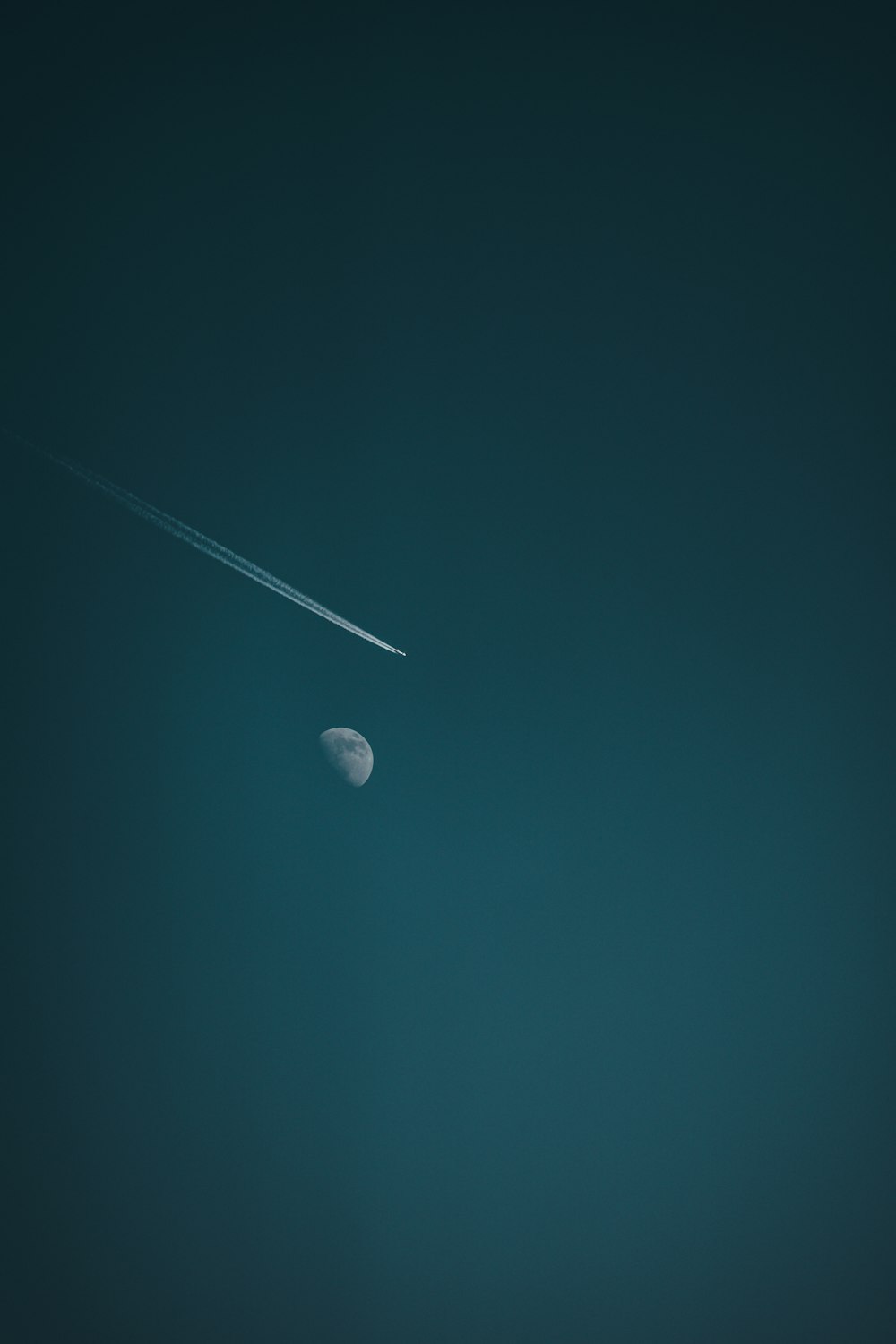 a plane flying in the sky with a moon in the background