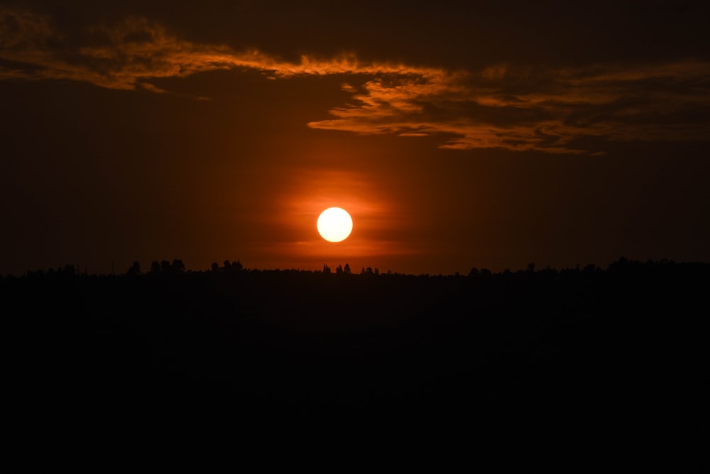 the sun is setting over the trees in the distance