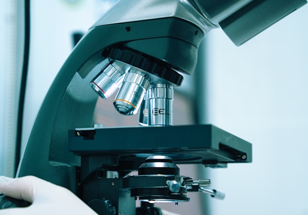 a gloved hand operating a microscope in a laboratory