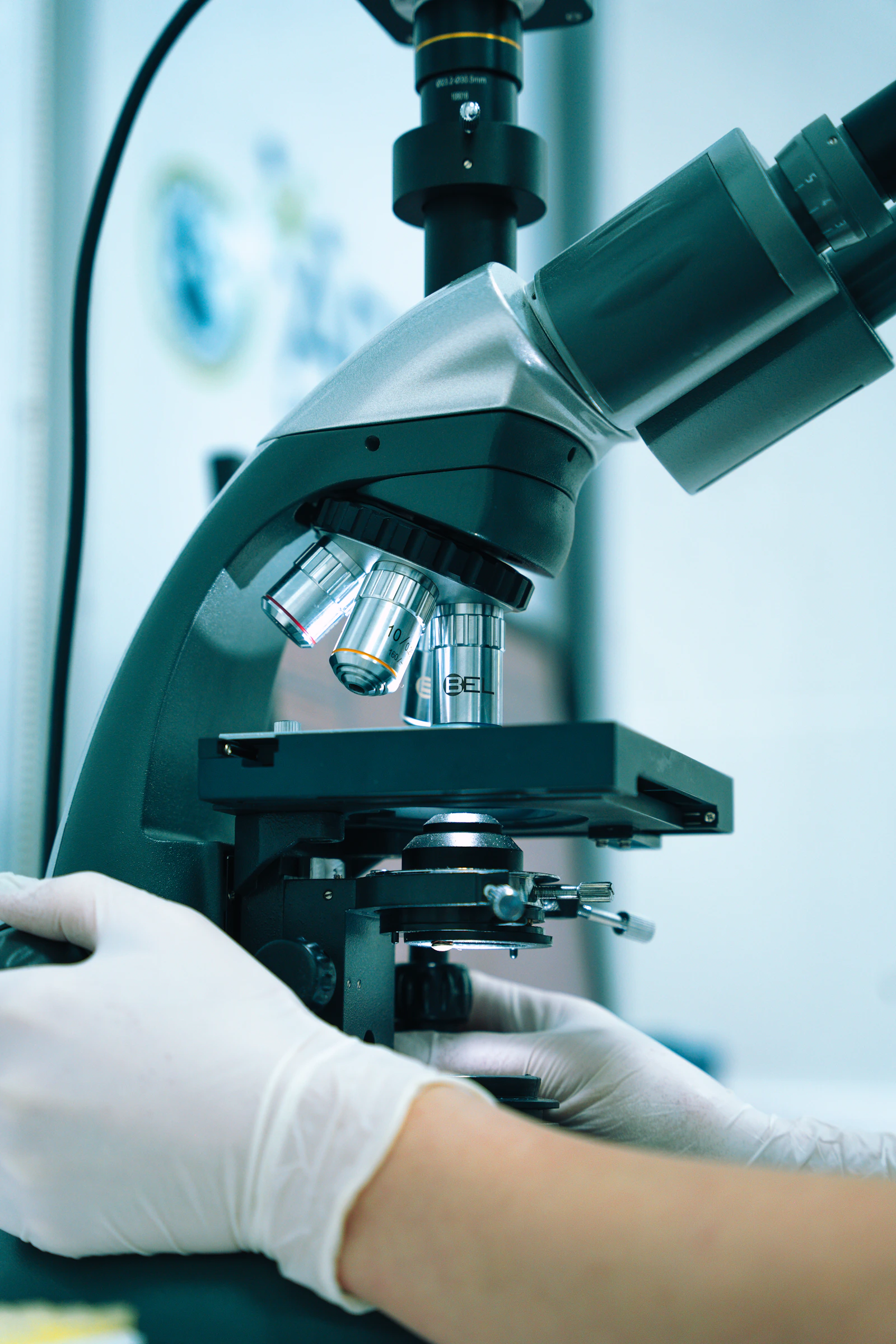 Lab technician operating a microscope to analyze a sample